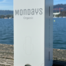 White Pad Dispenser with 'Mondays Organic' branding on a wooden surface with a scenic background