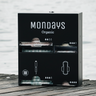 Stainless Steel Mondays QUAD Menstrual Product Dispenser painted black for 2 types of applicator tampon and 2 type of sanitary pad sitting on a wooden dock by a lake.